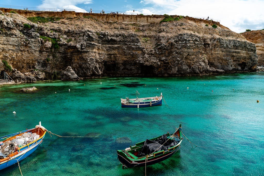 Is Malta Expensive? My Malta Budget Breakdown 2026 1 Scenic view of traditional Maltese boats in azure waters against a rocky coastline in Il-Mellieħa, Malta.