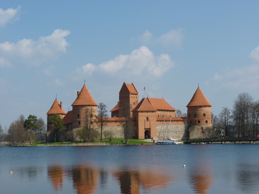 Scenic view of Trakai Island Castle with lake reflection under a blue sky.