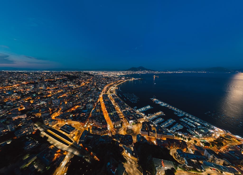 Stunning aerial view of Naples at night, showcasing the waterfront and city lights.