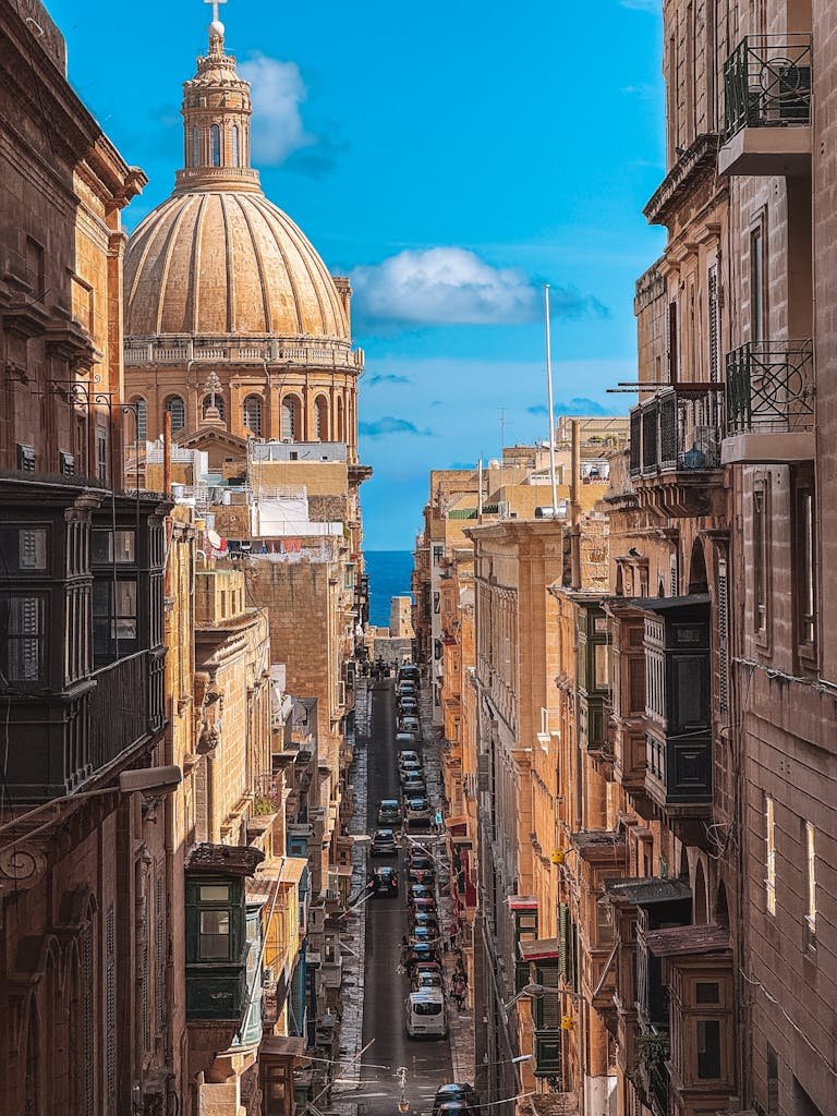 Stunning view of a narrow street in Valletta, Malta with historic architecture and a blue sky.