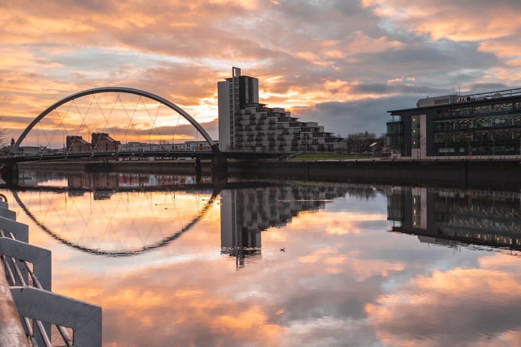 7 Day Scotland Road Trip Itinerary for First Timers 32 Stunning view of Glasgow's Clyde Arc reflecting in the River Clyde at sunset with modern architecture.