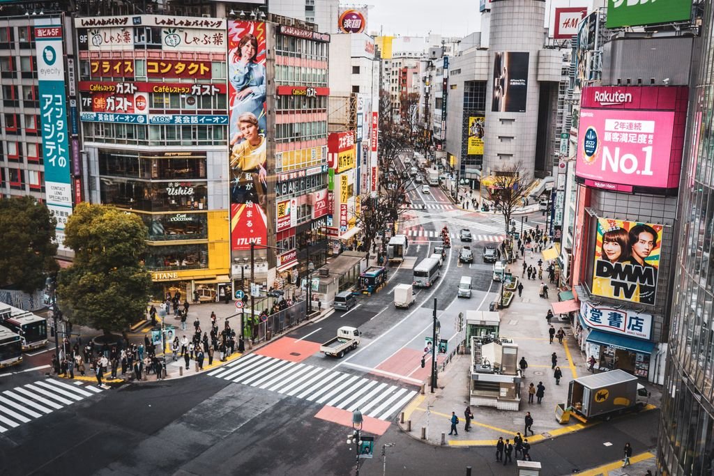 A bustling aerial view of Shibuya Crossing in Tokyo with vibrant signage and crowds.