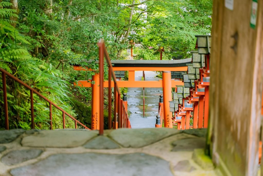 A serene walkway featuring multiple orange Torii gates in a Japanese garden.