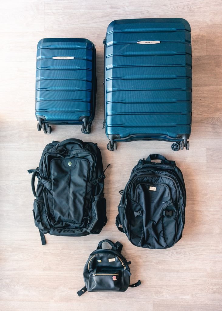 Aerial view of modern luggage and backpacks arranged on a wooden floor. Japan Packing List