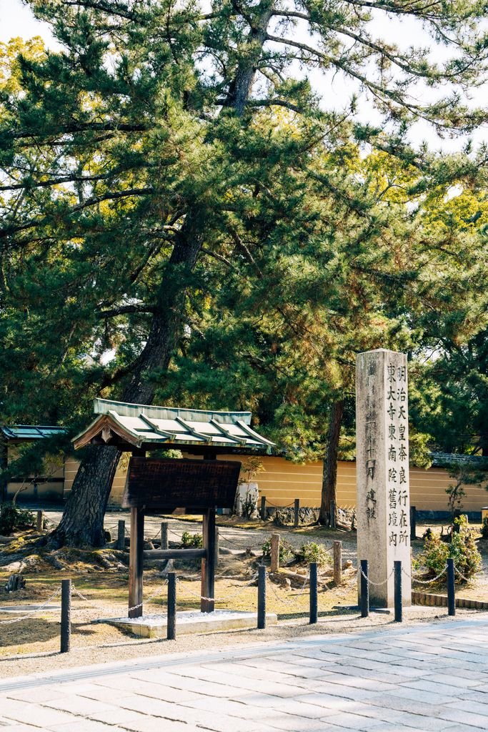 Nara Day Trip Guide: 10 Best Things to Do in Nara 12 Ancient stone marker amidst lush greenery in Nara Park, Japan, during a sunny day.