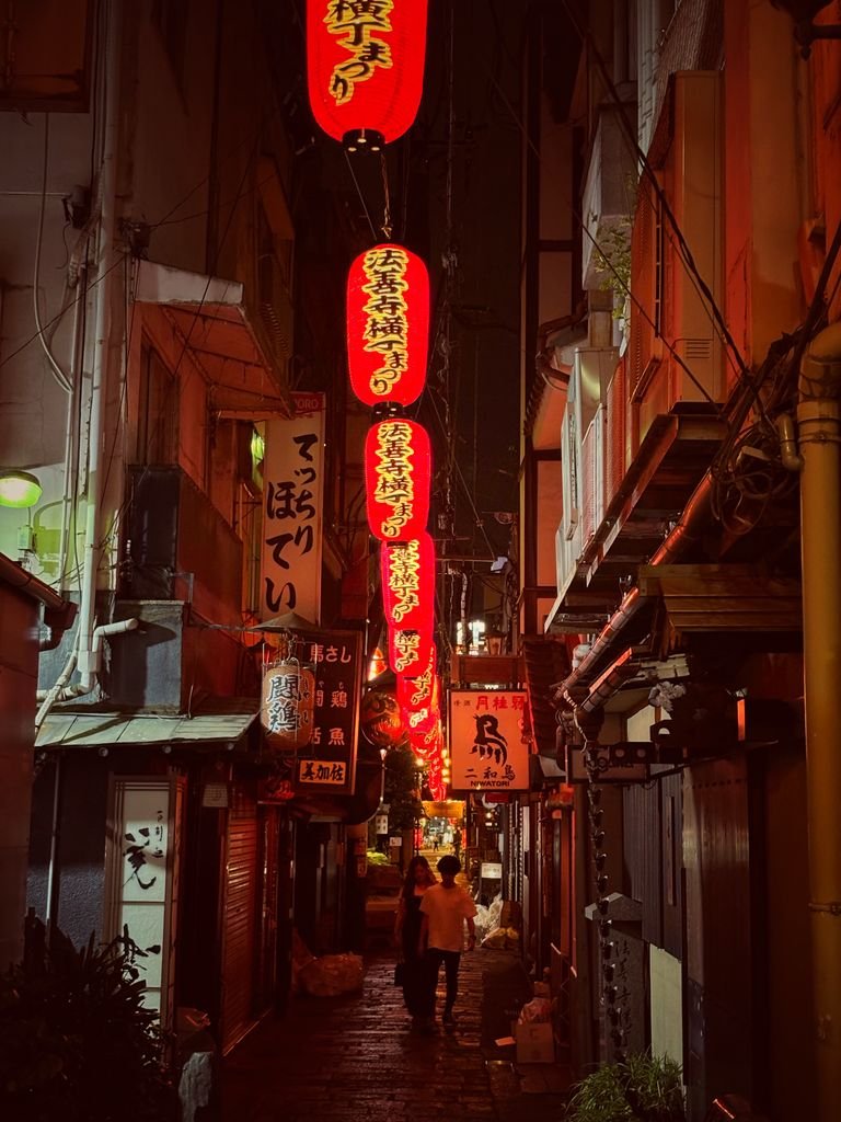 Atmospheric narrow alley in Dotonbori, Osaka, Japan illuminated by vibrant red lanterns.