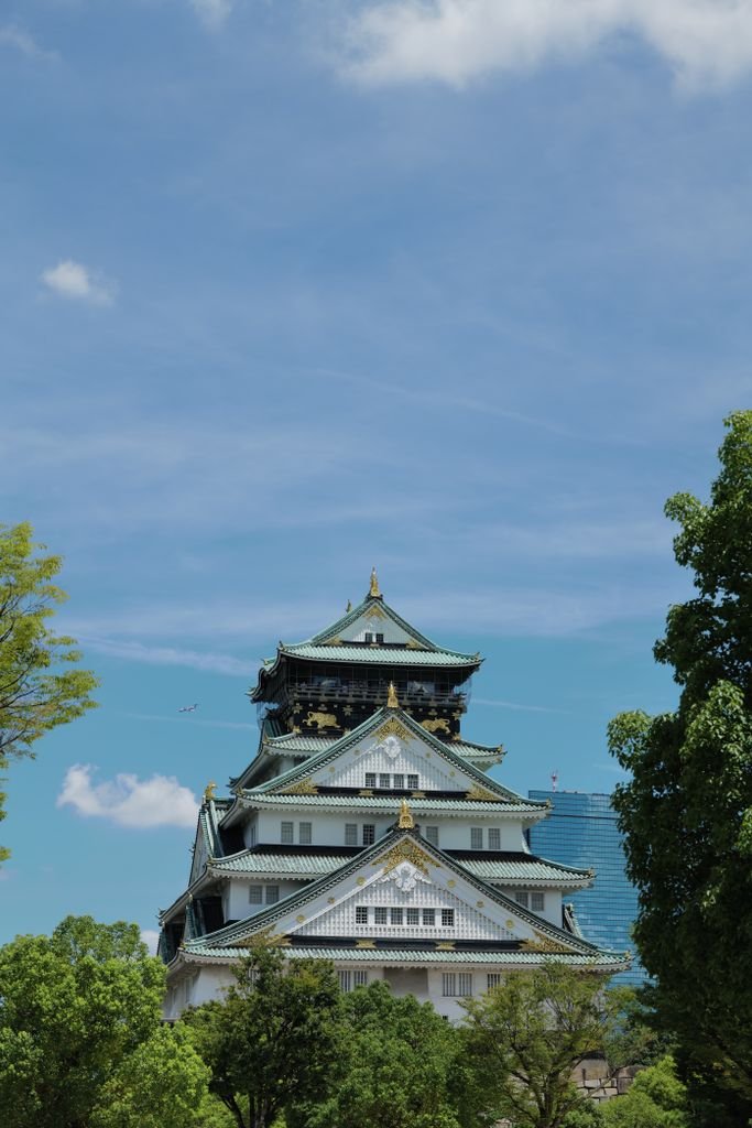 Majestic view of Osaka Castle with a backdrop of clear blue skies and surrounding greenery.