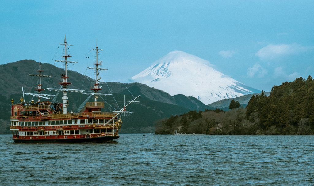 Pirate ship cruising on Lake Ashi with Mount Fuji in the background, surrounded by lush hills.