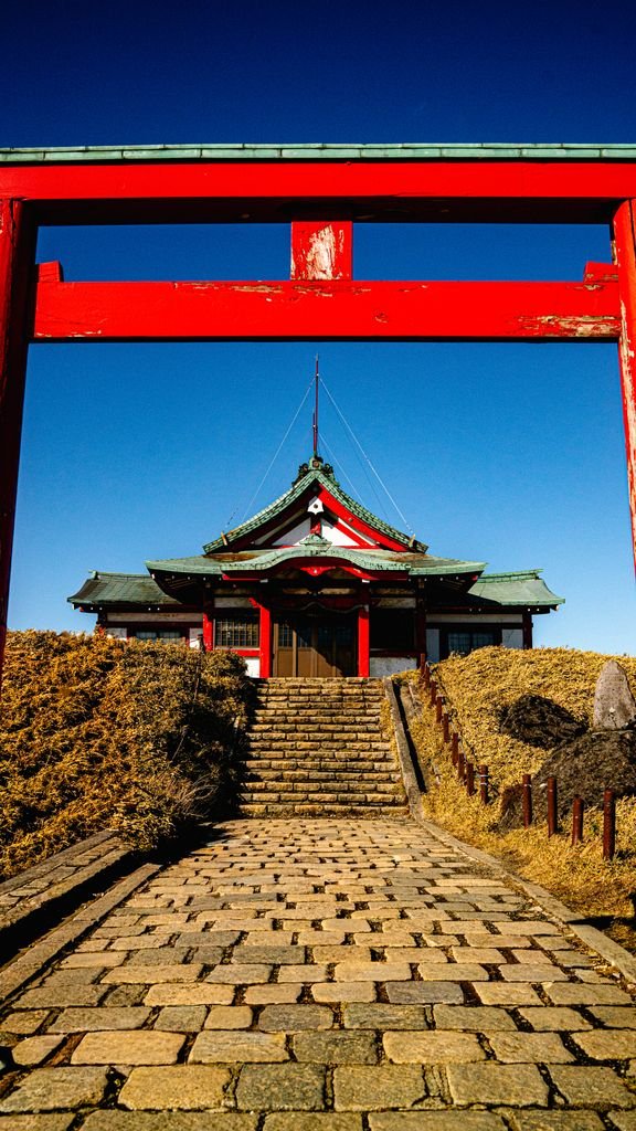 Scenic view of a red Torii gate and Hakone shrine under clear blue skies in Kanagawa, Japan.