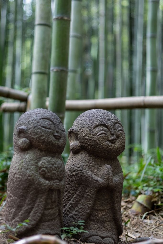 Arashiyama Bamboo Forest Kyoto: Is It Worth Visiting? 7 Serene stone statues amongst lush bamboo, capturing Zen tranquility in nature.