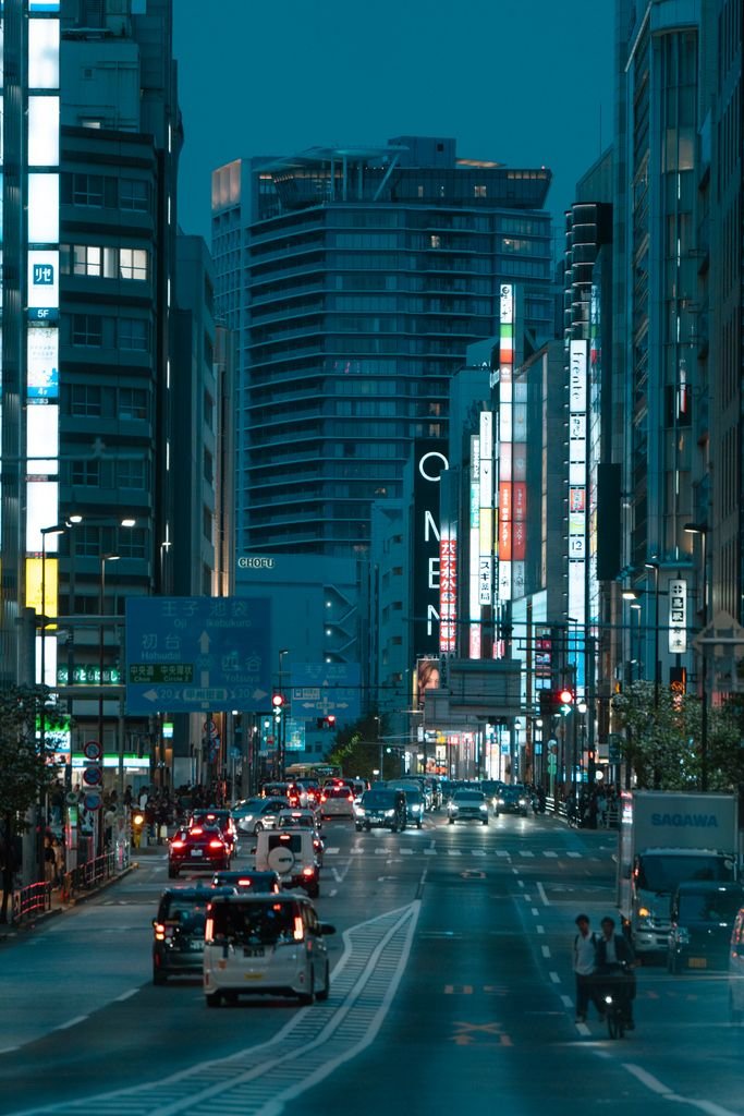 Tokyo city street bustling with traffic and vibrant neon lights during twilight.