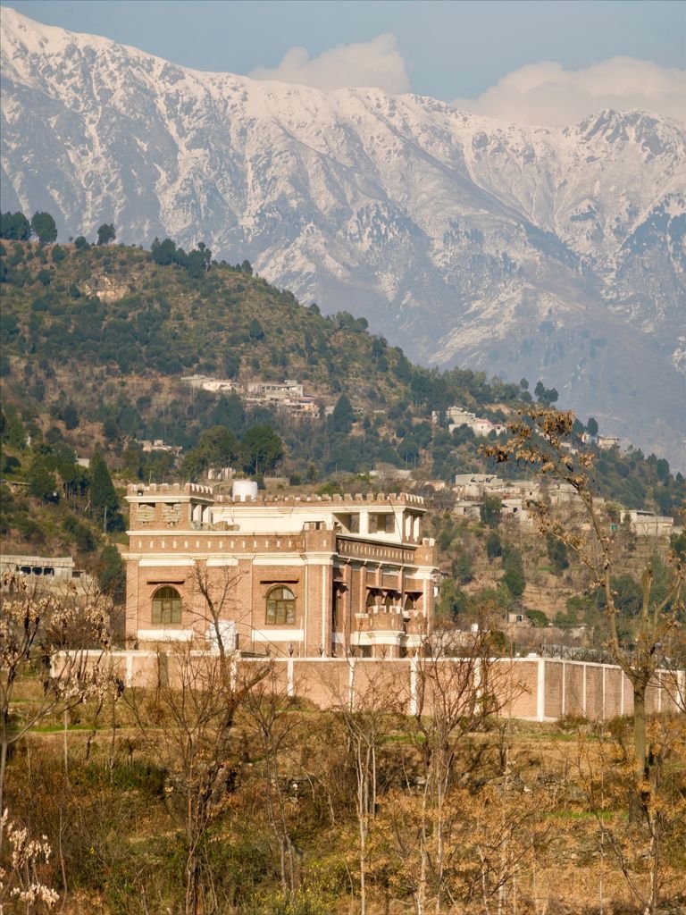 A colonial-style building set against the stunning mountainous backdrop of Swat Valley, Pakistan.