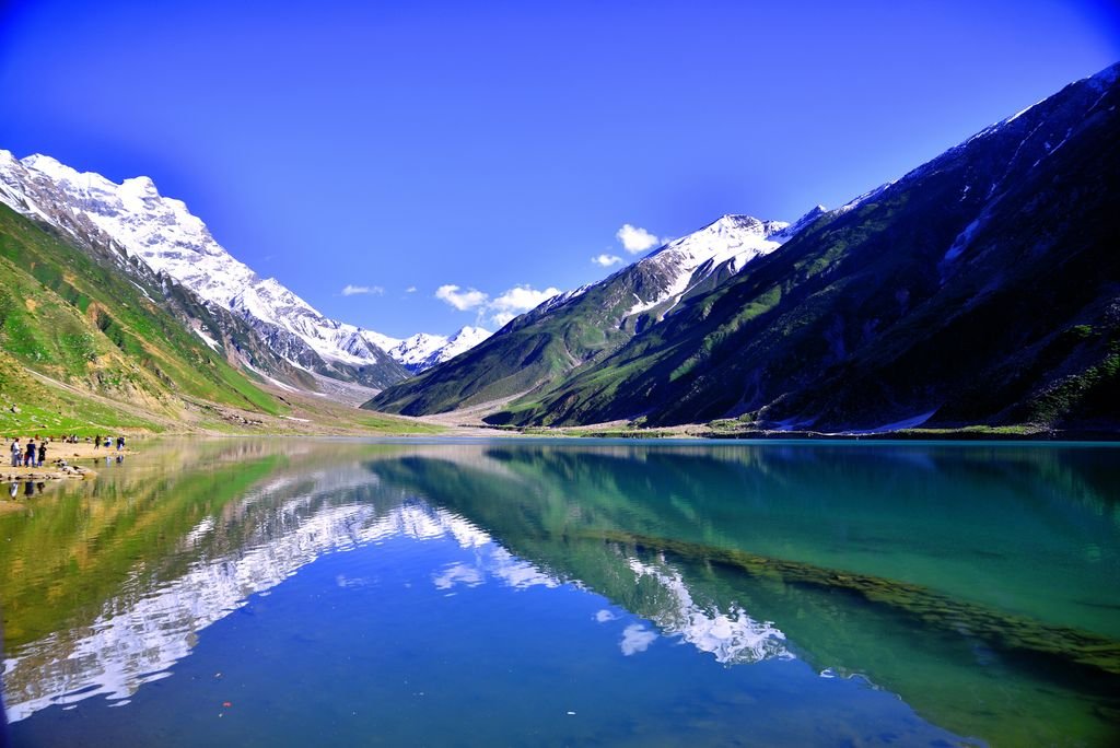 Breathtaking view of a reflective lake in Kaghan Valley, Pakistan, surrounded by snow-capped mountains.
