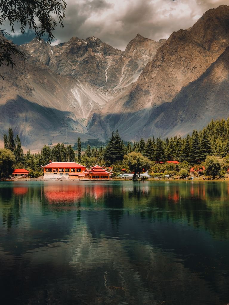 15 The Best Things to Do in Skardu for an Unforgettable Trip 3 Captivating shot of Shigar Lake in Skardu with red-roofed buildings and majestic mountains reflecting in the water. Things to do in Skardu
