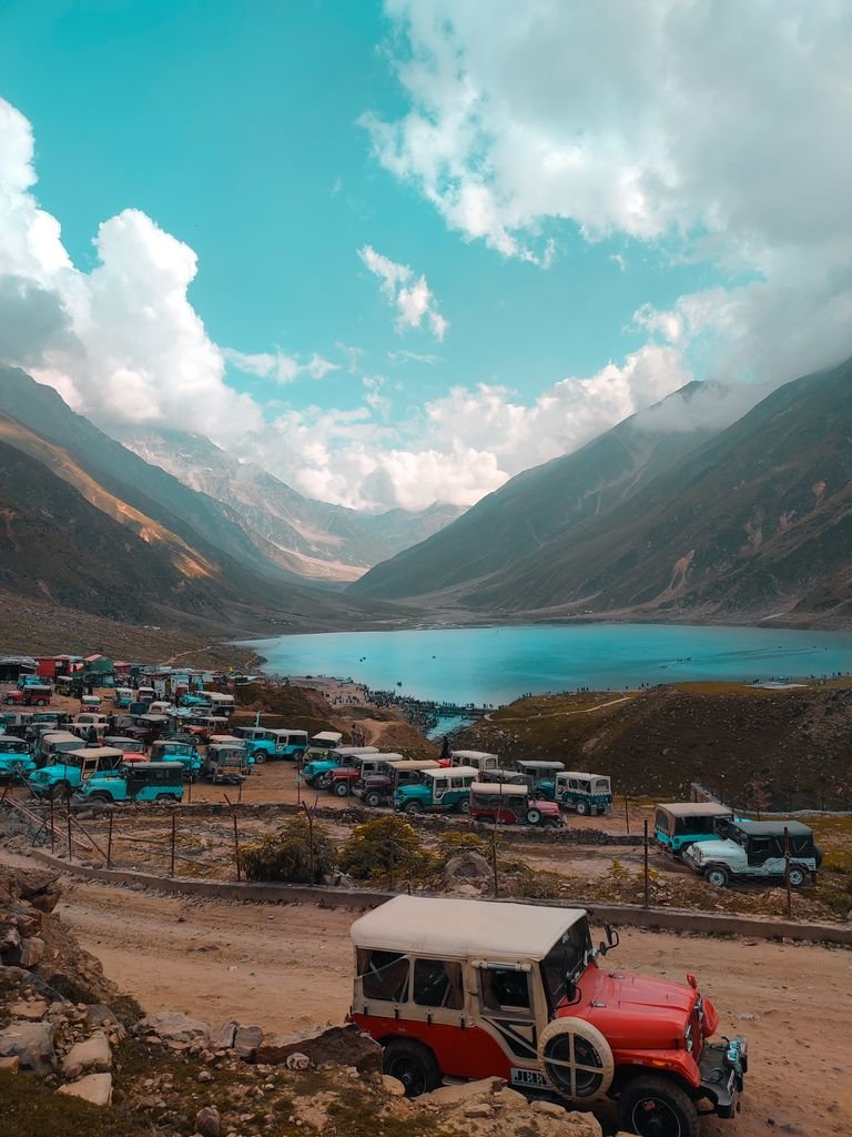 Explore the stunning lake valley with vibrant jeeps, scenic mountains, and clear skies.