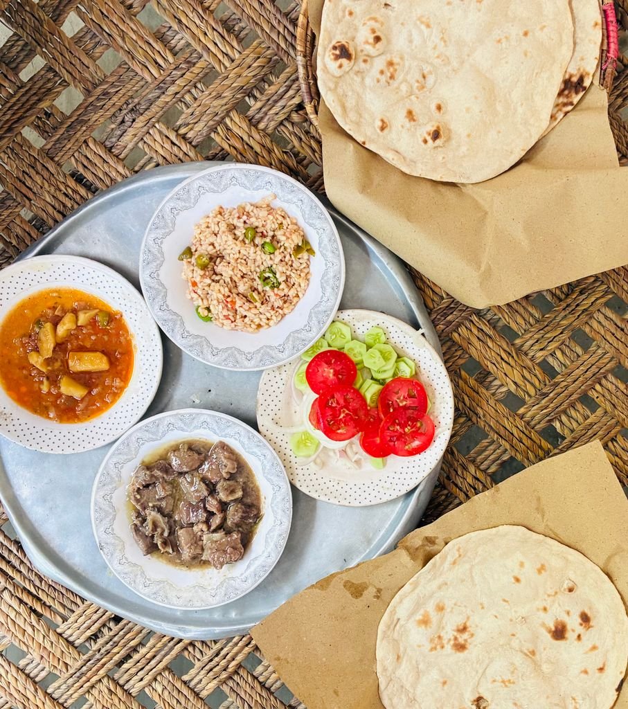 15 The Best Things to Do in Skardu for an Unforgettable Trip 13 Overhead view of a traditional Middle Eastern meal with flatbread, meat, rice, and vegetables.