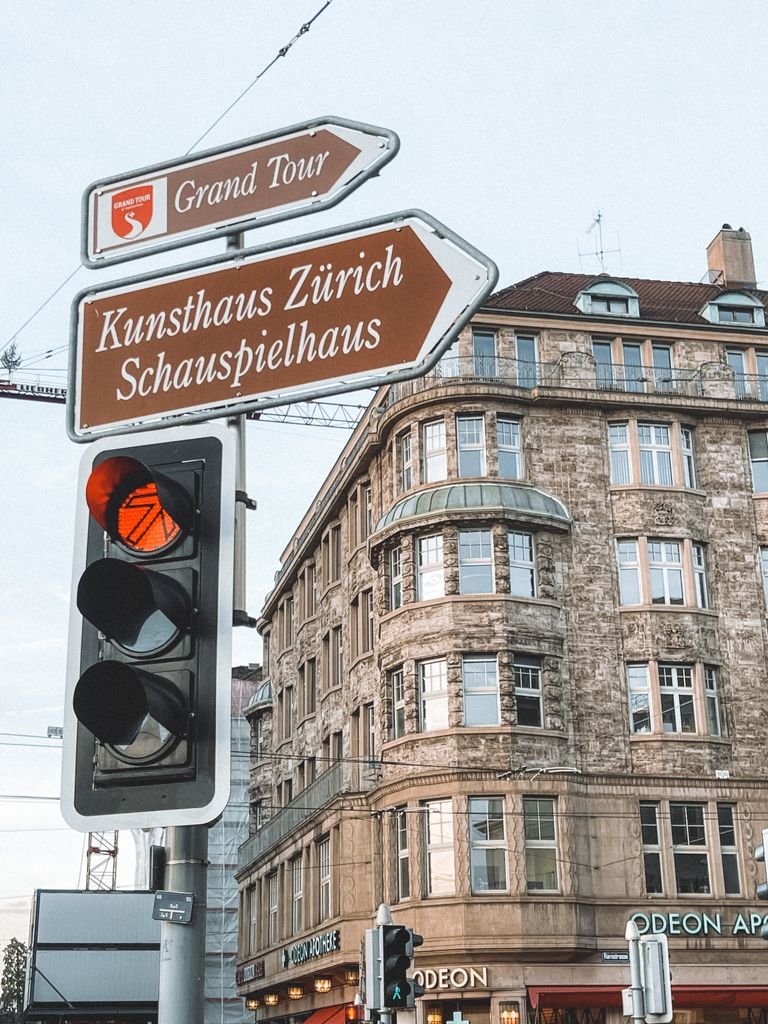 City street scene in Zürich with directional signs to Kunsthaus and Schauspielhaus and historic architecture.