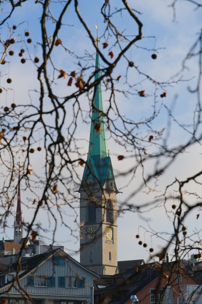 View of Fraumünster Church through winter branches, showcasing Zurich's historic charm.
